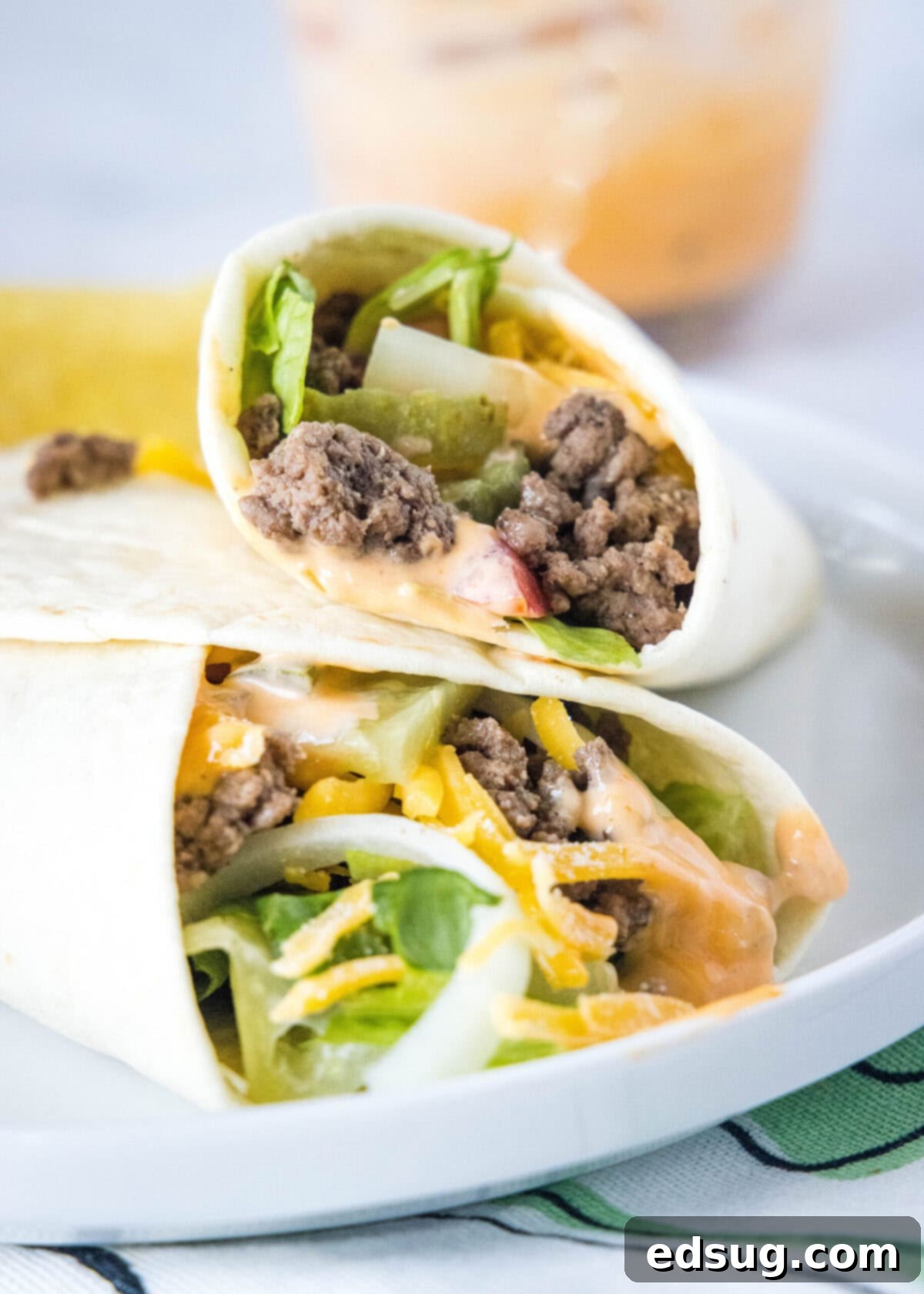 A burger wrap leaning against another burger wrap on a plate