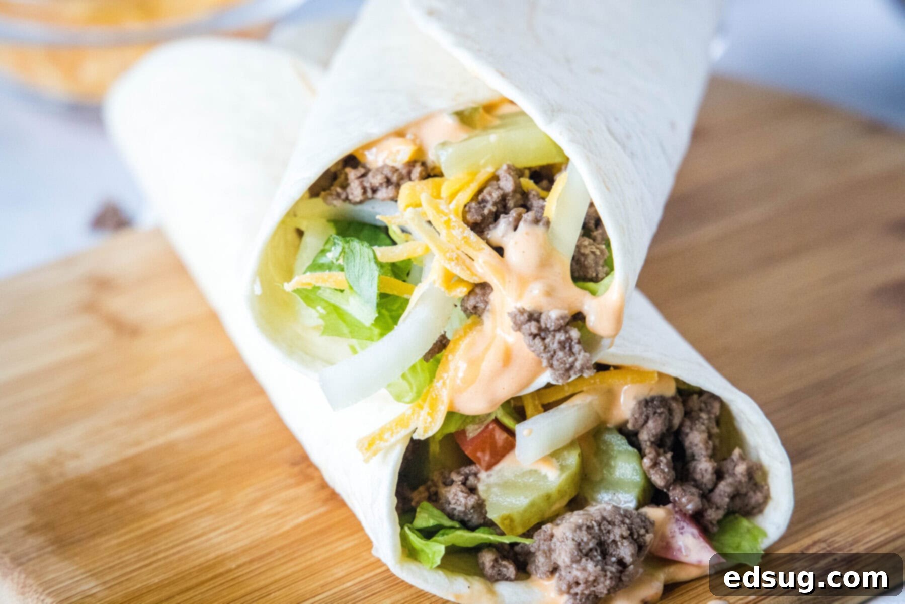 Two burger wraps stacked on top of each other at an angle, on top of a cutting board