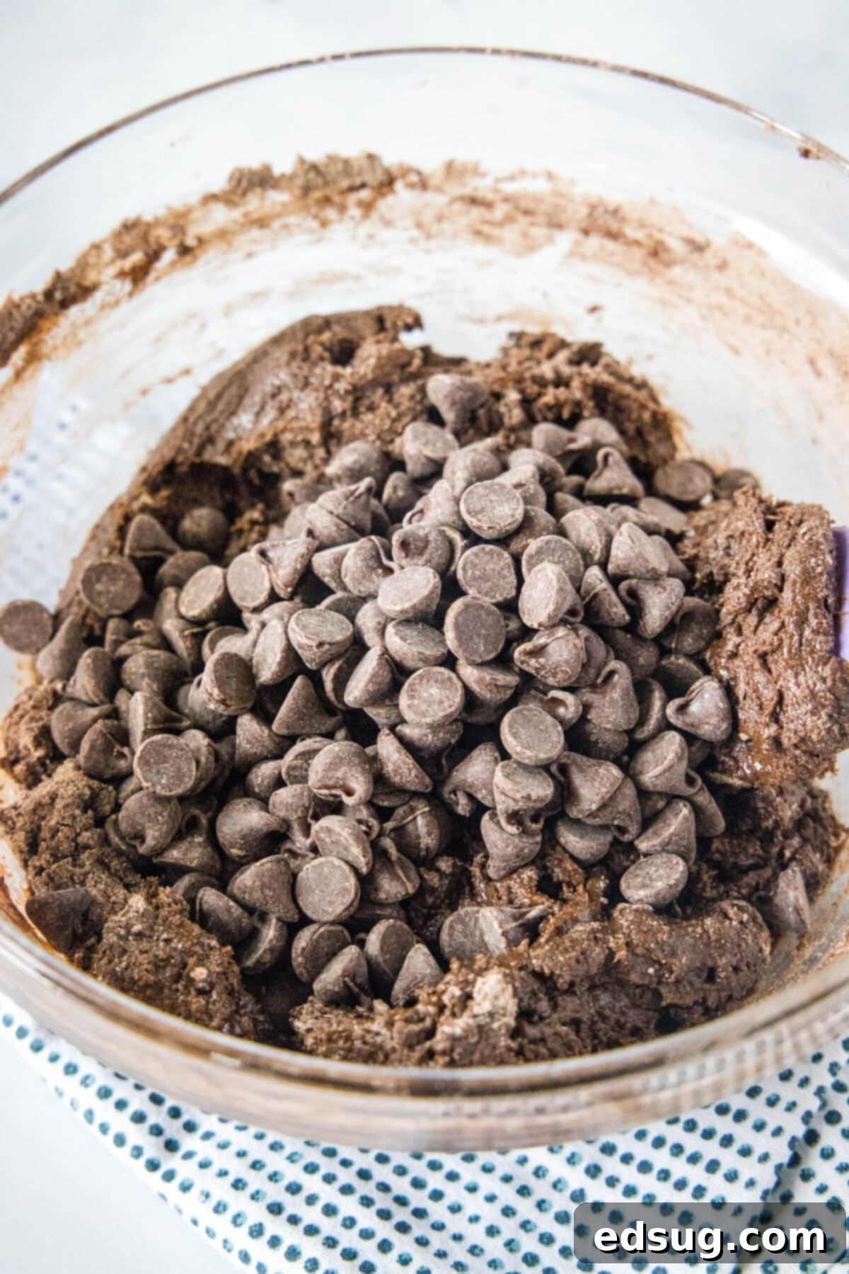 These 30-minute cake mix brownies only use 5 ingredients, and they're moist, soft, and packed full of chocolate flavor A mixing bowl filled with thick, rich brownie batter, generously studded with semi-sweet chocolate chips, ready for baking