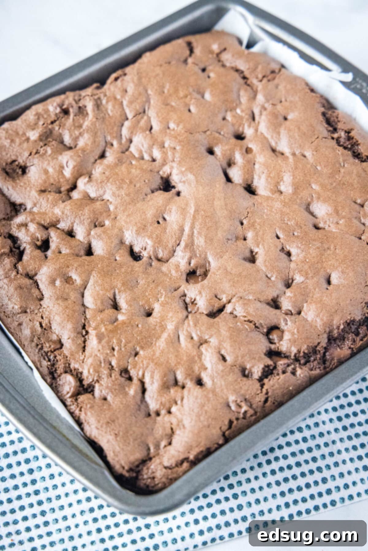 These 30-minute cake mix brownies only use 5 ingredients, and they're moist, soft, and packed full of chocolate flavor Overhead view of a square baking dish filled with freshly baked, fudgy brownies, their tops slightly crinkled and edges perfectly set, still warm from the oven