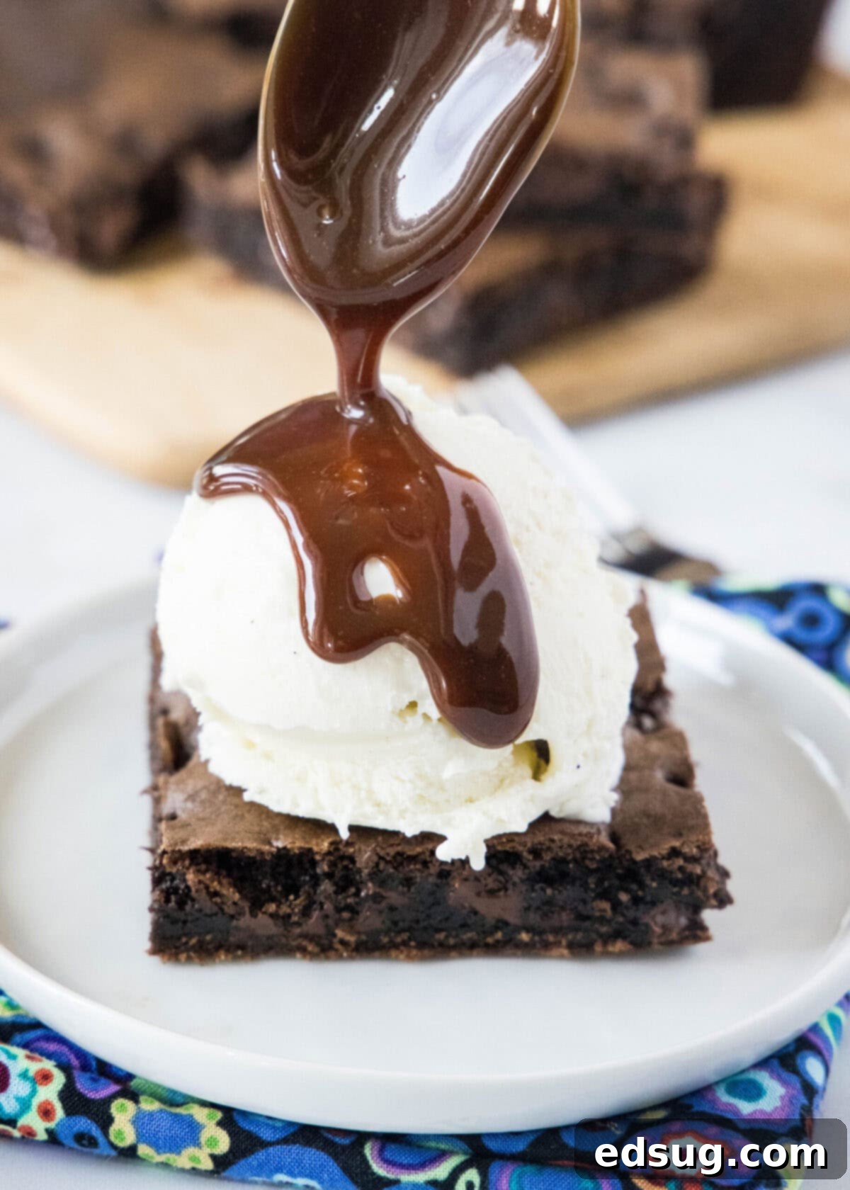 These 30-minute cake mix brownies only use 5 ingredients, and they're moist, soft, and packed full of chocolate flavor A spoon expertly drizzling rich fudge sauce over a scoop of vanilla ice cream, perfectly complementing a square of fudgy brownie on a pristine white plate