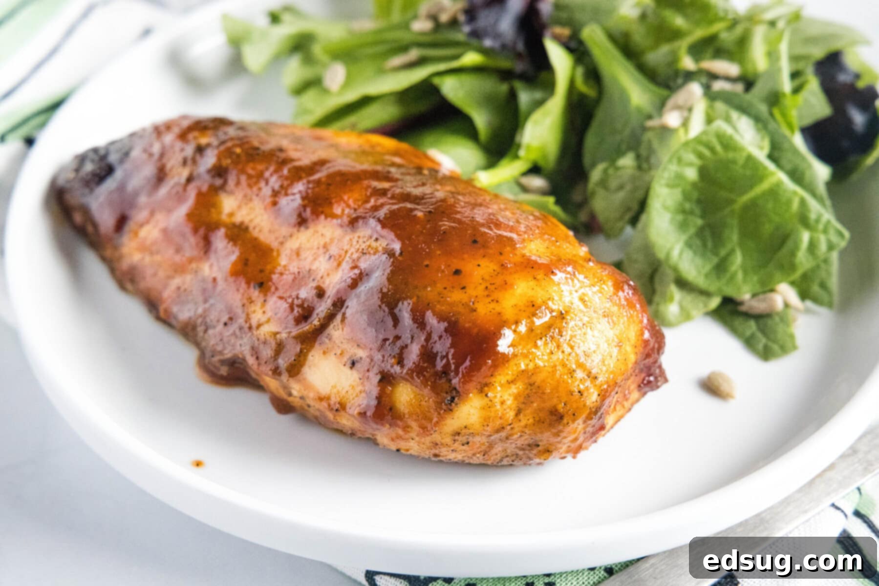 Overhead view of a plate with a fresh green salad and a succulent BBQ chicken breast, ready to be enjoyed.