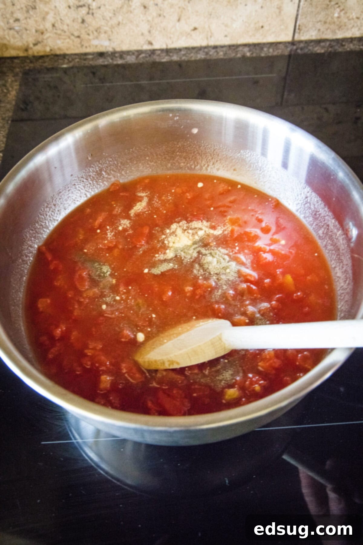 Homemade ketchup is tangy, salty, smooth, and so much better than the store-bought kind. Plus, it's easy to make and takes less than an hour. A wooden spoon stirring vibrant red tomatoes, clear vinegar, and a mix of seasonings in a gleaming pot on the stove.