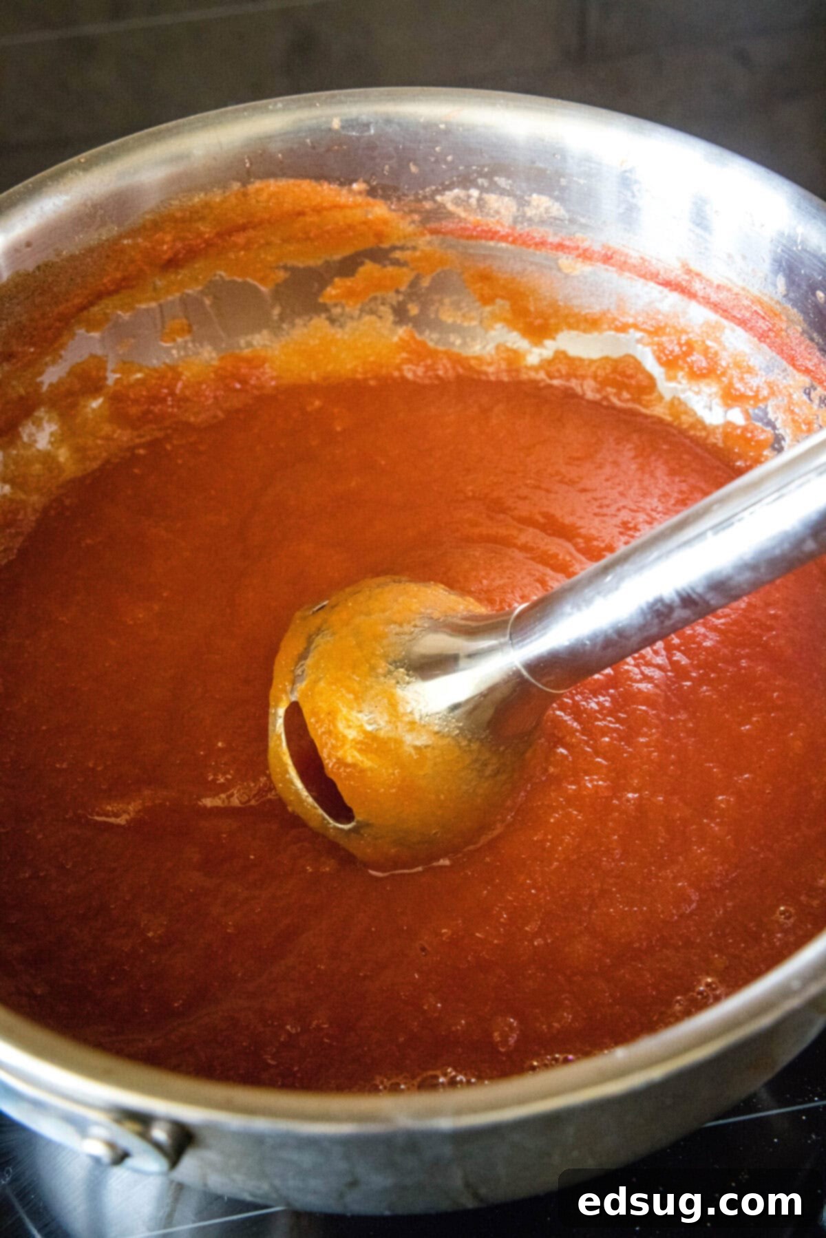 Homemade ketchup is tangy, salty, smooth, and so much better than the store-bought kind. Plus, it's easy to make and takes less than an hour. A stick blender vigorously blending the cooked ketchup directly in the pot, transforming it into a smooth, uniform consistency.