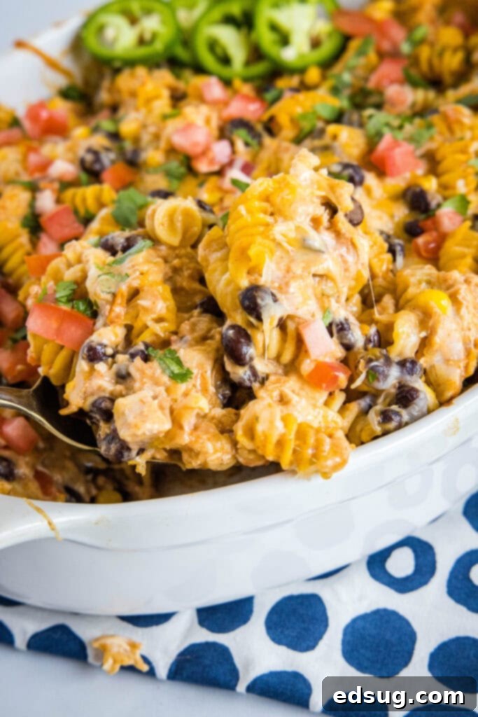 Zesty Southwest Chicken Casserole 2 Scooping generous portions of creamy Fiesta Chicken Casserole out of a baking dish, showcasing its rich texture and cheesy topping.