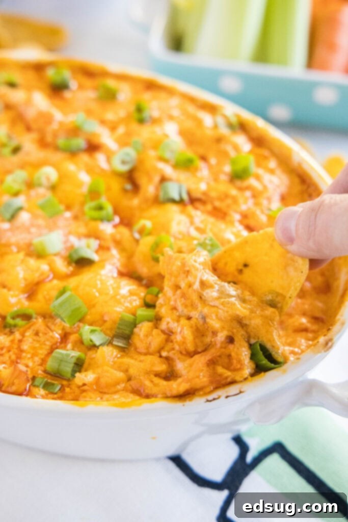 Ultimate Instant Pot Buffalo Chicken Dip 8 Fritos scoops corn chips generously piled next to a dish of buffalo chicken dip, inviting guests to enjoy