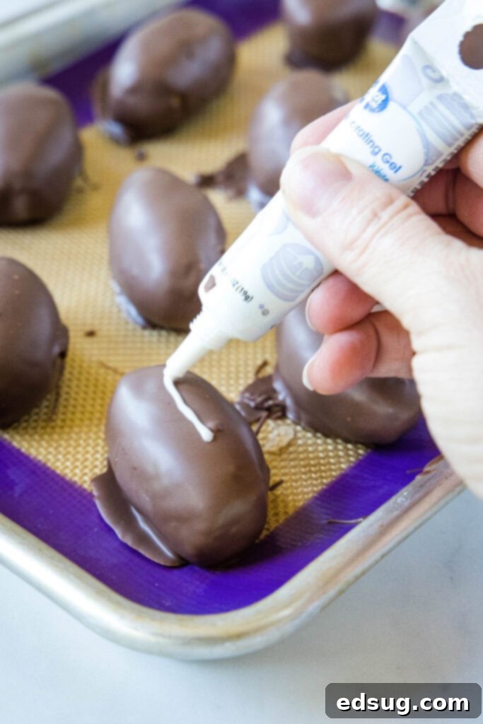 Applying white laces to chocolate-covered peanut butter footballs with decorating gel