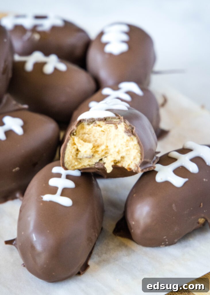 A chocolate covered peanut butter football with a bite taken out, showing the creamy interior