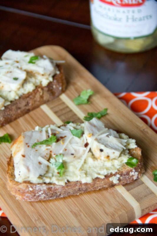 Delicious open faced chicken sandwich with vibrant artichoke pesto on a wooden board, ready to eat.