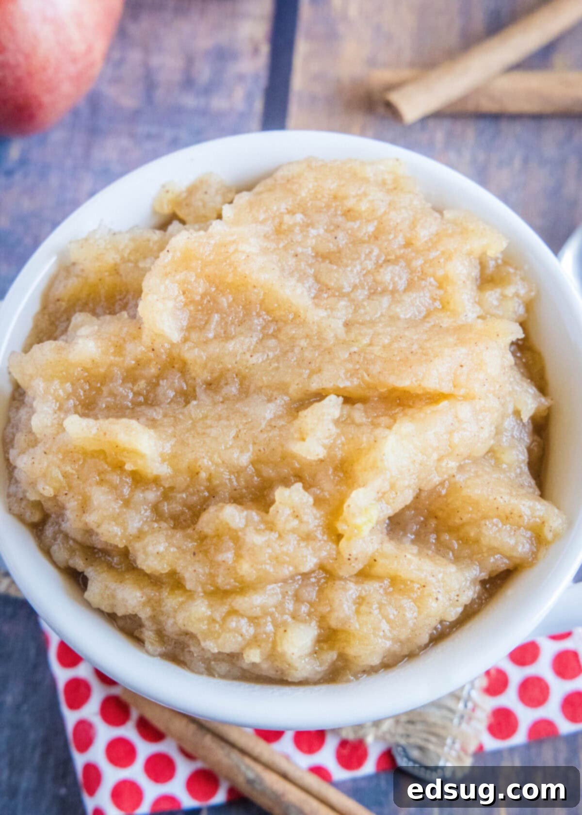 This homemade applesauce recipe is tart, lemony, not too sweet, bursting with apple flavor, and only takes 40 minutes to make.  Overhead view of a bowl of applesauce surrounded by cinnamon sticks