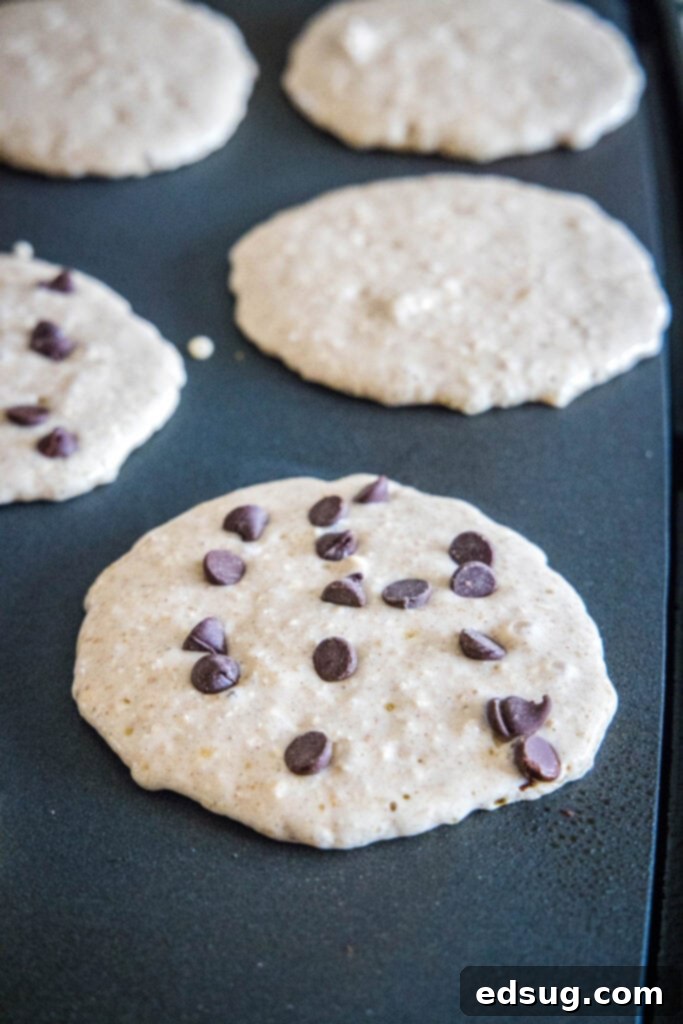 Wholesome Oat Pancakes 5 pancakes cooking on a griddle, showing bubbles forming on the surface