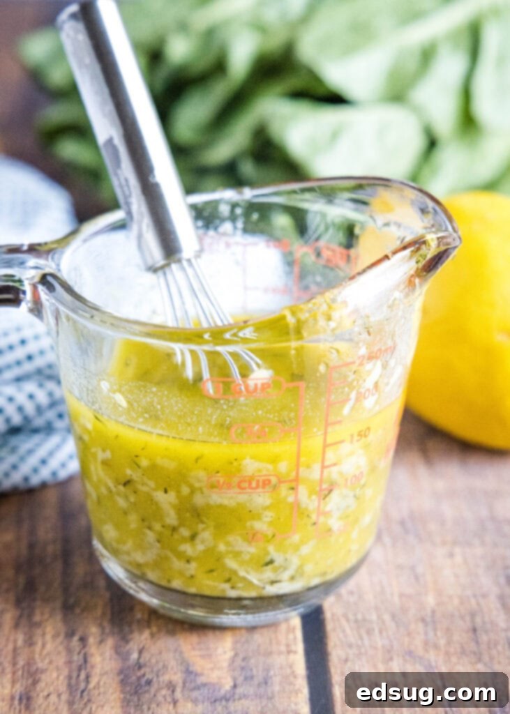 Freshly made lemon garlic vinaigrette in a liquid measuring cup, showcasing its bright color and perfect consistency, ready to be poured.