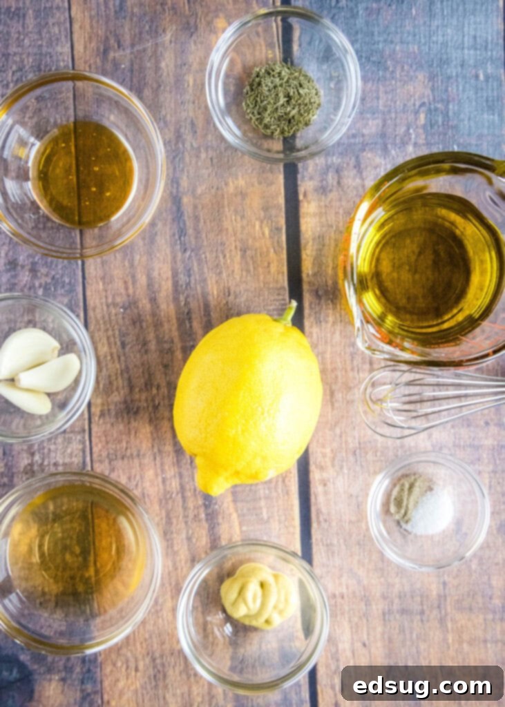All the fresh ingredients for lemon garlic vinaigrette laid out on a wooden cutting board, including whole lemons, garlic cloves, a bottle of olive oil, and various spices.