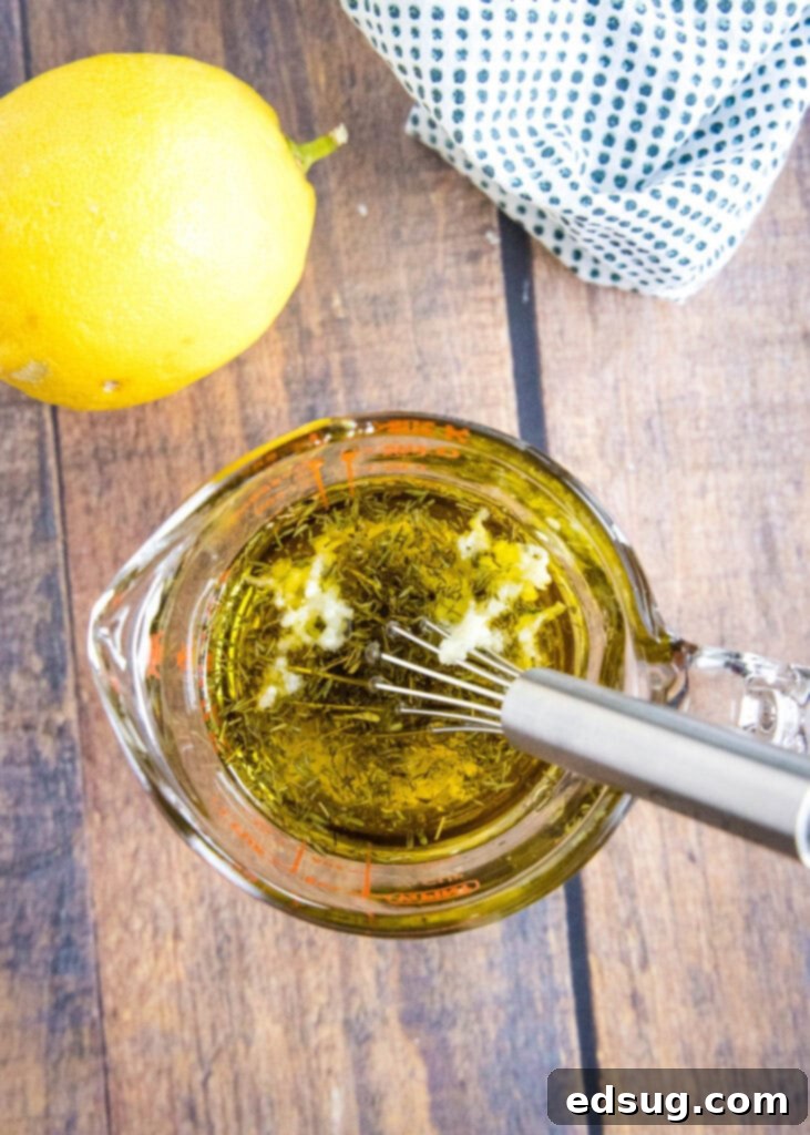 All the lemon garlic vinaigrette ingredients mixed together in a clear glass measuring cup, showing the consistency before a final shake.