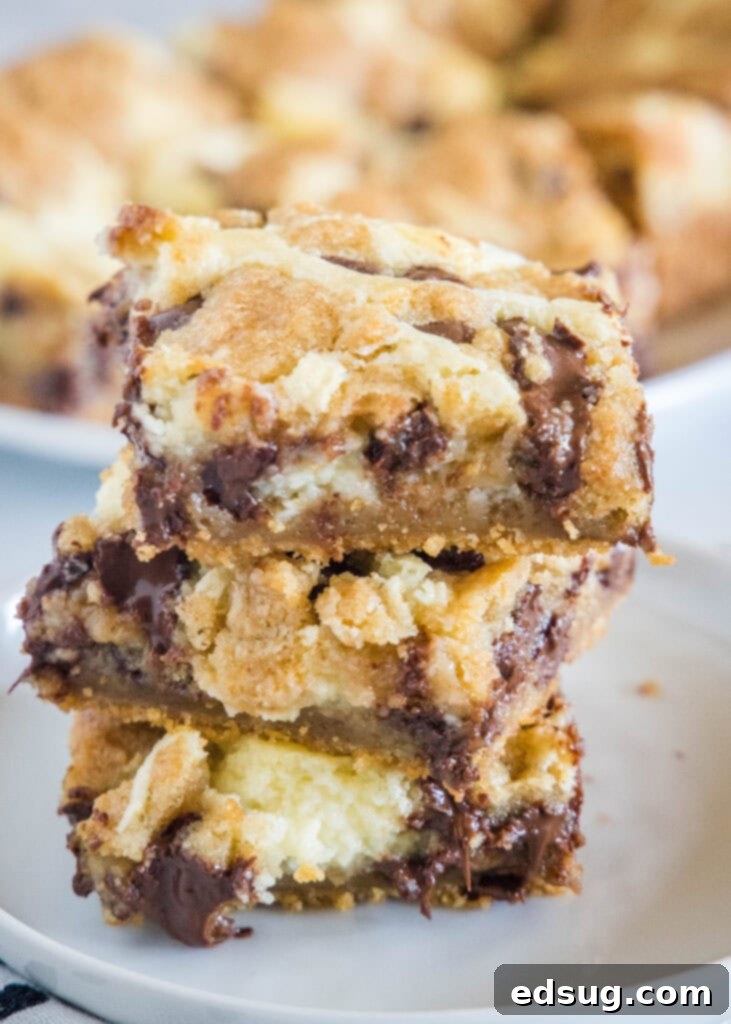 Choc-Chip Cheesecake Dream Bars 2 chocolate chip cookie cheesecake bars stacked on a white plate