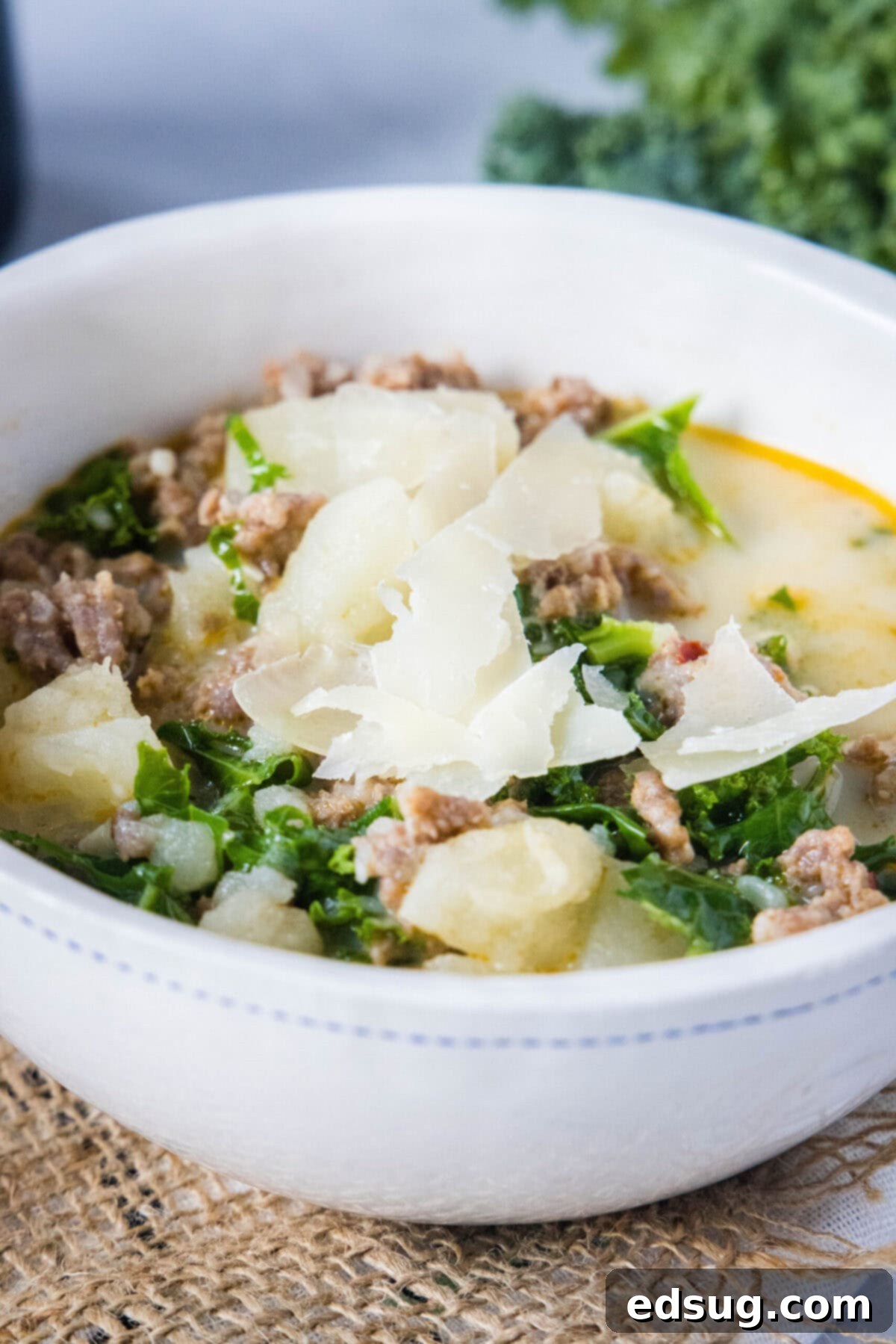 This copycat Olive Garden Zuppa Toscana is rich, hearty, healthy, loaded with potatoes and sausage, and easy to make in the Instant Pot. Close up of a bowl of Zuppa Toscana topped with parmesan cheese