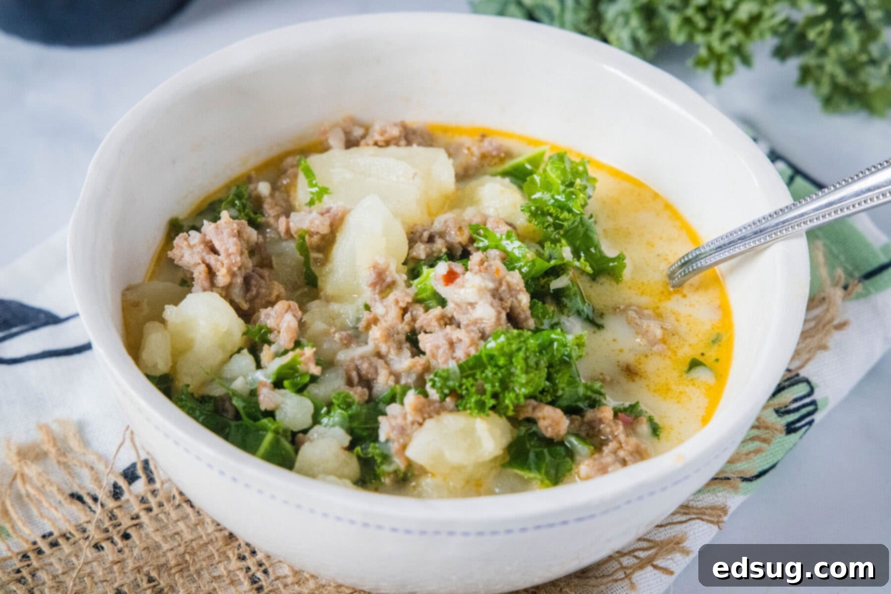 This copycat Olive Garden Zuppa Toscana is rich, hearty, healthy, loaded with potatoes and sausage, and easy to make in the Instant Pot. Close up of a bowl of Zuppa Toscana with a spoon in it