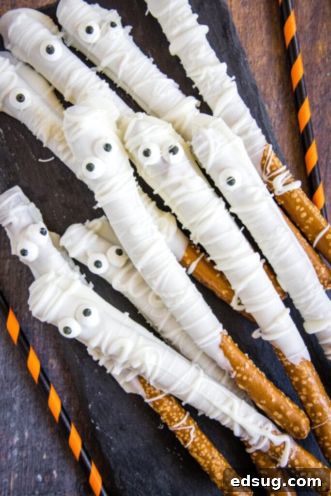 Bandaged Bites 2 A festive tray overflowing with adorable white chocolate mummy pretzel rods, ready for a Halloween party.