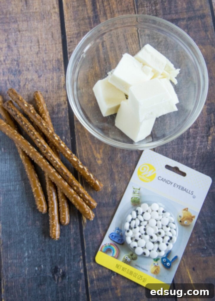 Bandaged Bites 3 The essential ingredients for mummy pretzels laid out: pretzel rods, white melting chocolate wafers, and a container of various candy eyes.