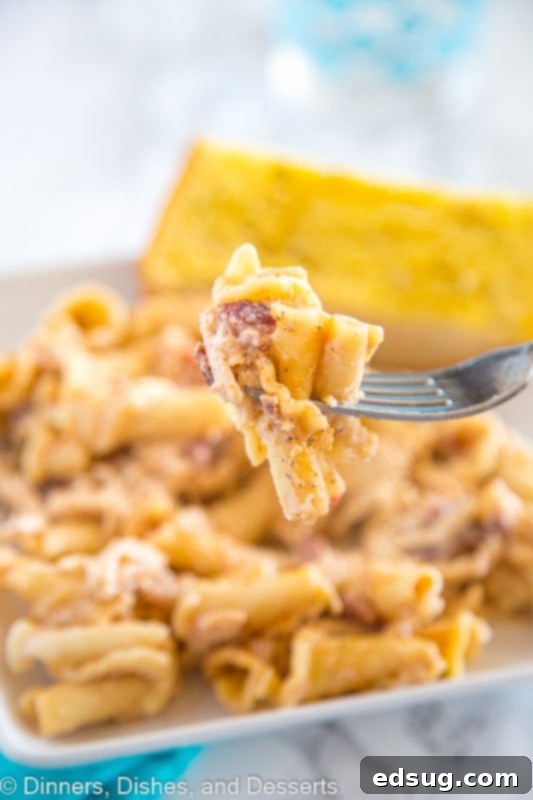 Smokey Garlic Chicken Pasta - A creamy chicken pasta recipe with a tons of flavor. A little smokey, a little peppery, and so good! A fork lifting a bite of Smokey Garlic Chicken Pasta from a bowl