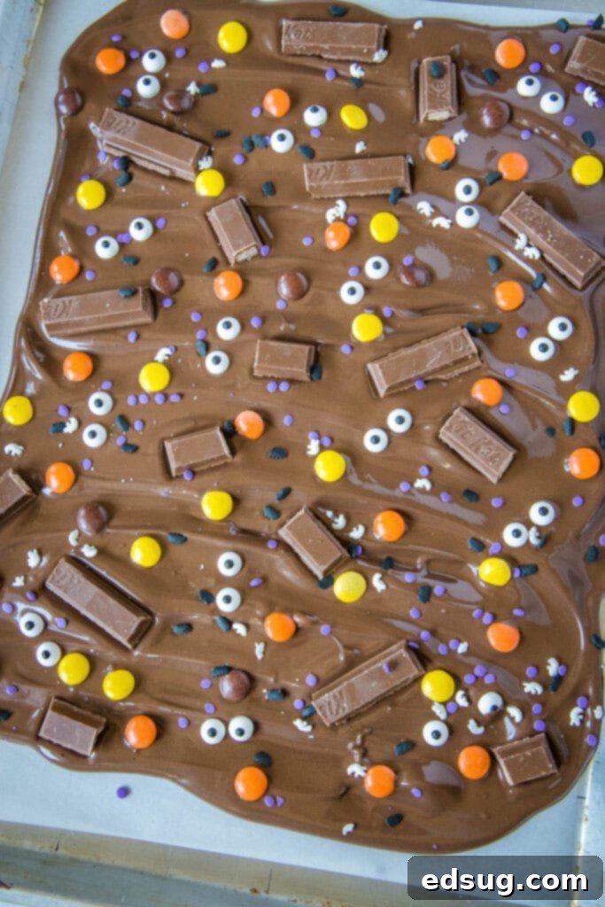 Monster Mash Bark 2 Vibrant Halloween candy bark ready to set up on a baking sheet, adorned with candy, sprinkles, and candy eyes
