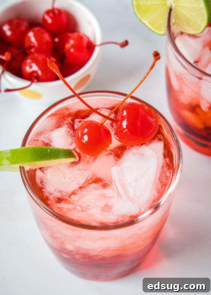 looking down on a glass with a dirty shirley cocktail garnished with cherry and lime