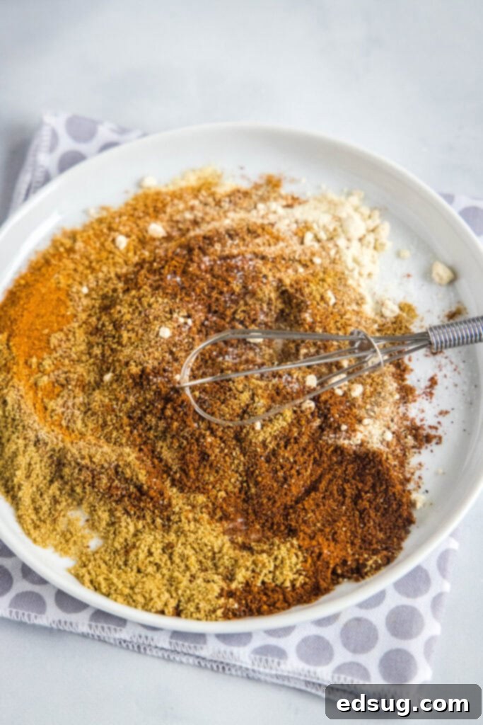 This 5-minute fajita seasoning is spicy, smoky, salty, and loaded with cumin and garlic, perfect for shrimp, chicken, or steak fajitas. A whisk mixing together spices on a plate