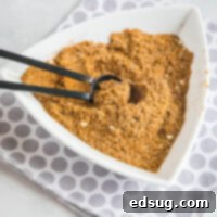 Ultimate Fajita Blend 2 A white triangular bowl filled with fajita seasoning with a serving spoon