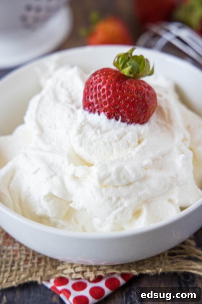 Fluffy Homemade Whipped Cream 2 a strawberry sitting in a bowl of homemade whipped cream, invitingly presented