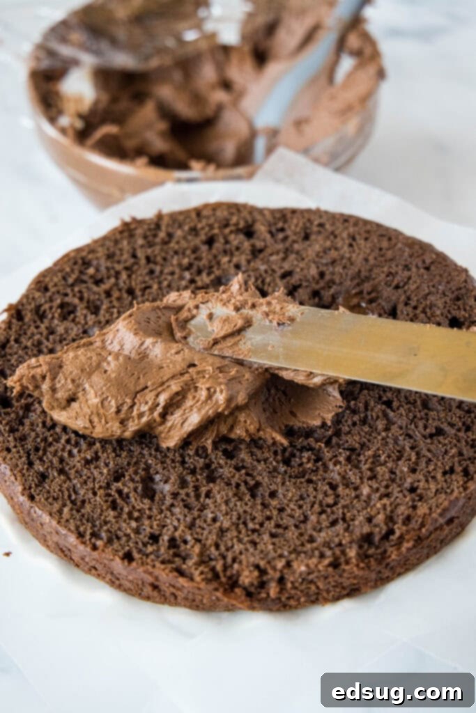 Obsidian Chocolate Cascade Cake 4 spreading chocolate frosting on a cake