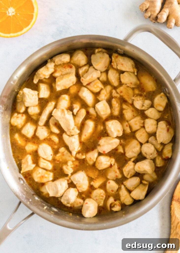 Zesty Orange Chicken 4 Orange chicken pieces cooking in a skillet with the sauce, simmering to perfection.