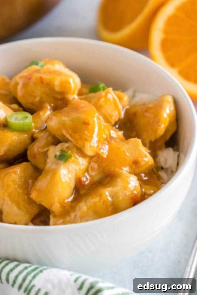 Zesty Orange Chicken 7 A beautifully presented bowl of orange chicken and rice, garnished with green onions and sesame seeds.