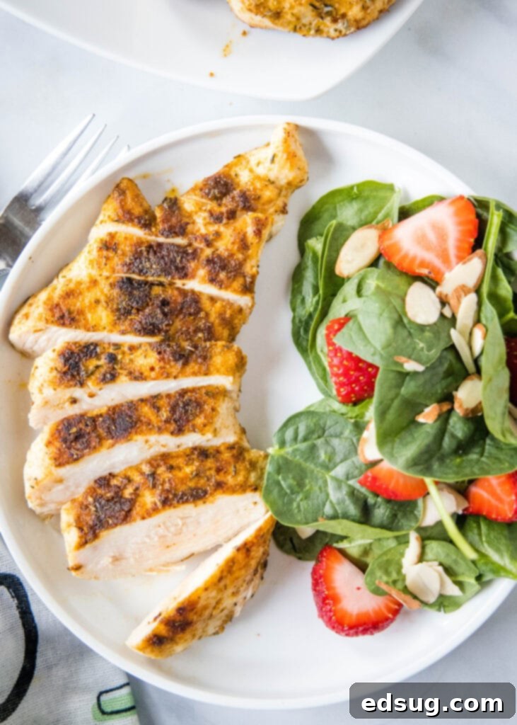 looking down on a plate with sliced blackened chicken and spinach salad