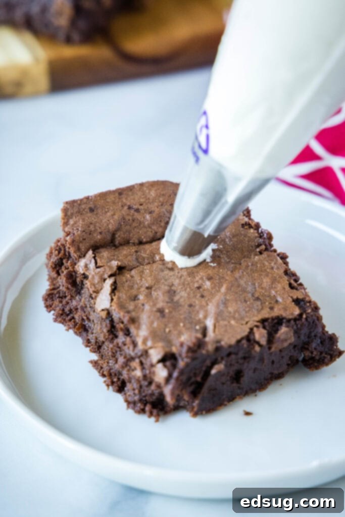 Piping vanilla frosting onto a brownie square to create the base for a Santa hat.