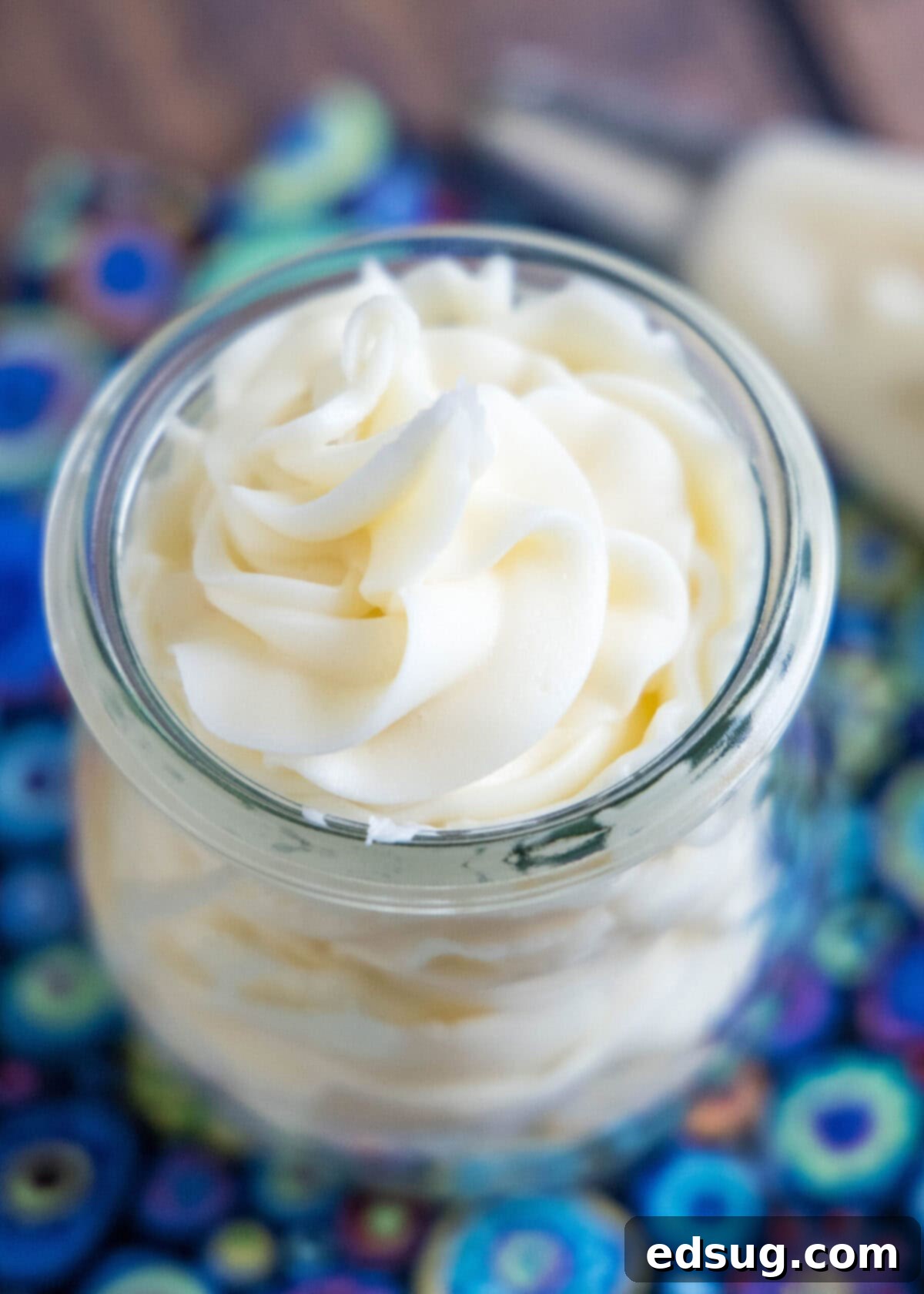 Close-up overhead view of a jar of vanilla frosting next to a piping back