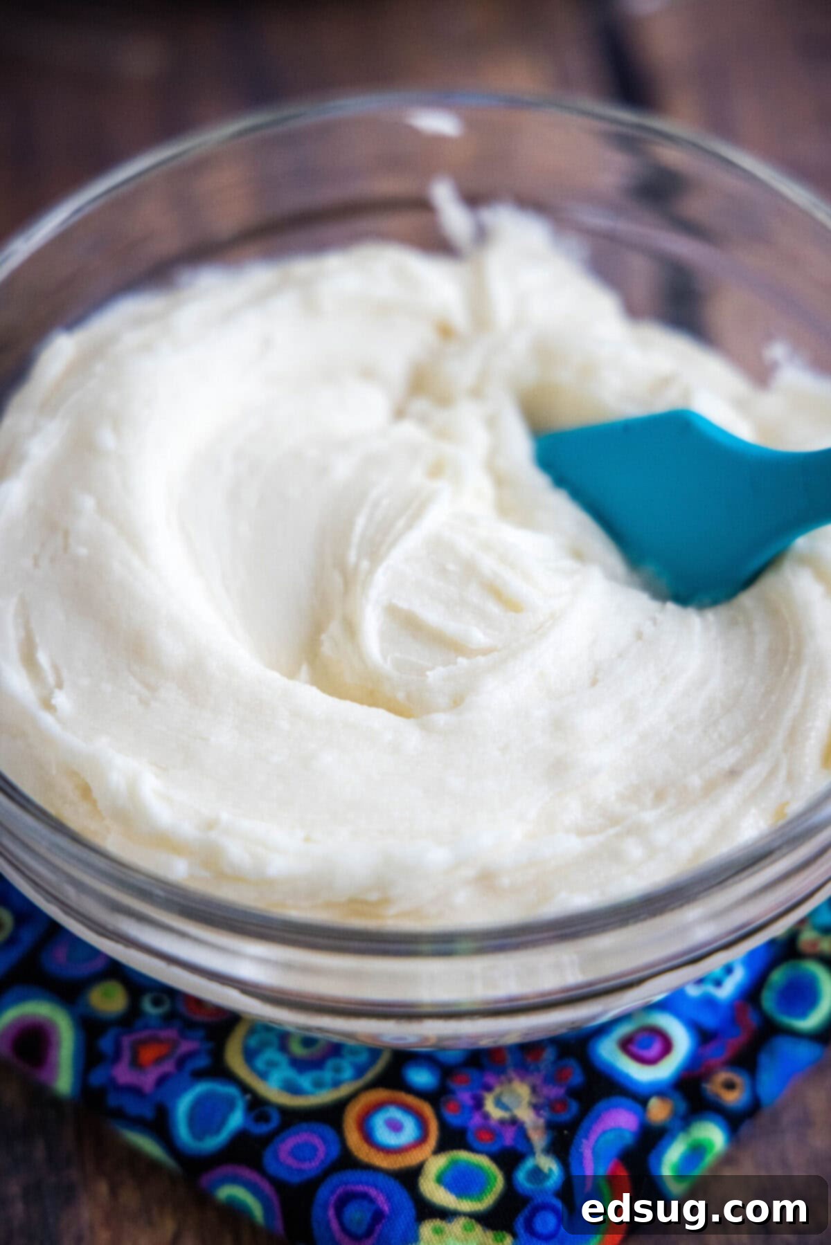 A bowl of vanilla frosting with a spatula in it