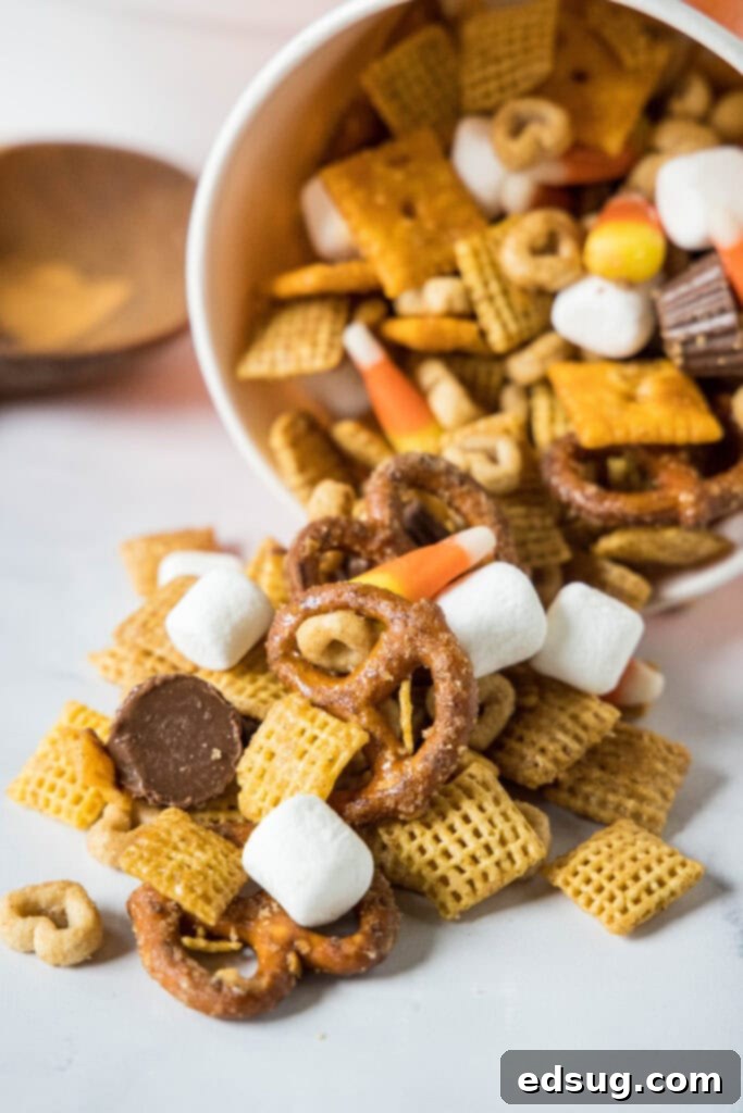 Cozy Autumn Crunch 6 orange bowl on its side with fall snack mix coming out of it