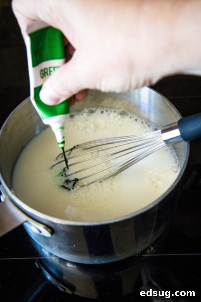 Grinchy Hot Chocolate 4 Green food coloring being added to white hot chocolate in a saucepan, creating the iconic Grinch color.