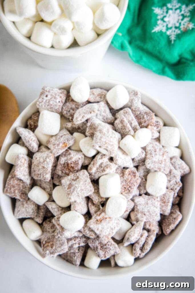 Cozy Cocoa Muddy Buddies 2 Looking down on a bowl filled with hot chocolate muddy buddies, garnished with mini marshmallows