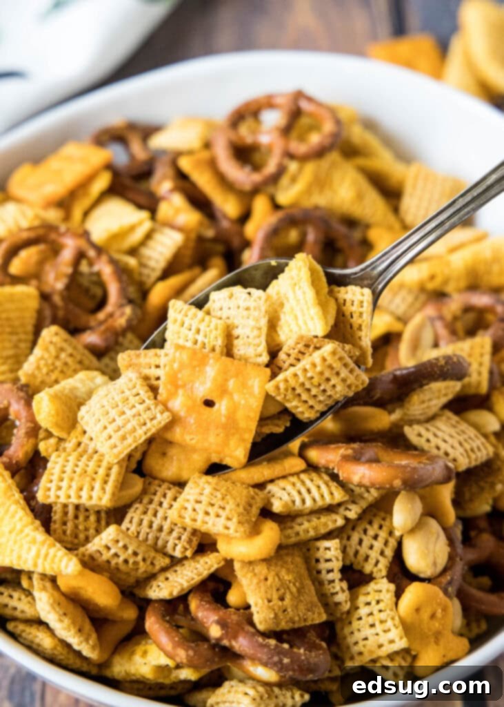 spooning cheese chex mix out of a bowl