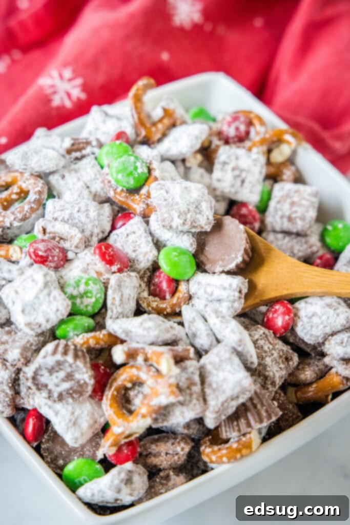 Reindeer Munch Mix 5 a spoon scooping reindeer muddy buddies out of a bowl