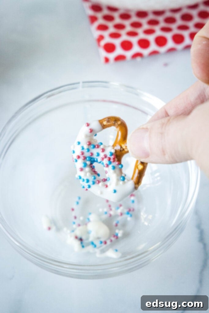 Stars and Stripes Twists 4 A freshly dipped pretzel on parchment paper, being decorated with patriotic sprinkles.