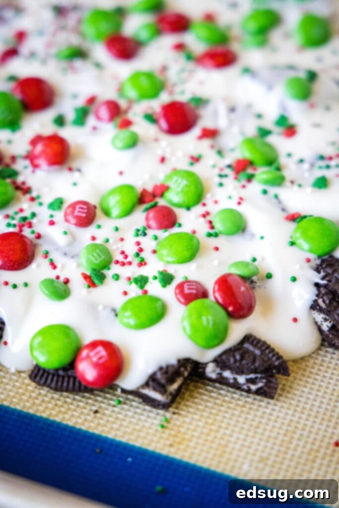 Holiday Candy Bark 5 A sheet of white chocolate Christmas bark, still on the parchment-lined baking tray, with toppings embedded, waiting to be cut.