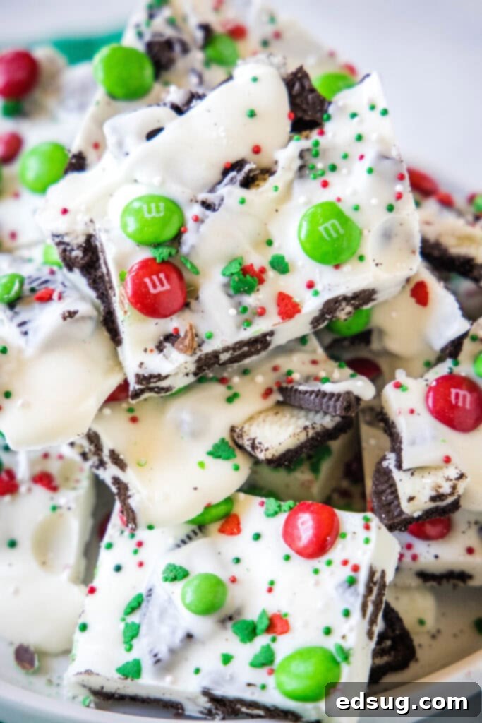 Holiday Candy Bark 8 Close-up of neatly sliced Christmas bark on a white plate, highlighting the dense topping of Oreos and M&M's.