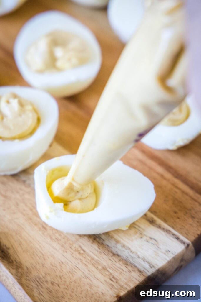 Touchdown Deviled Eggs 5 piping deviled egg mixture into eggs