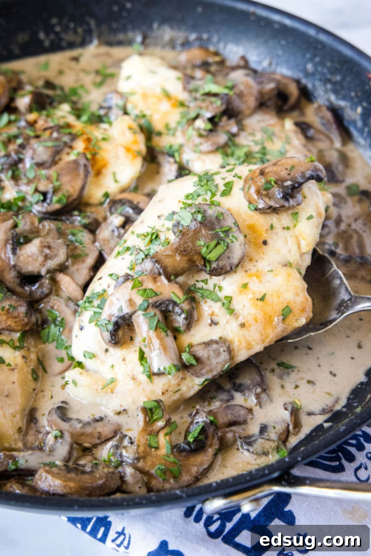 Easy and comforting chicken with mushroom sauce has juicy and tender meat smothered in a rich, herbaceous, and garlicky mushroom cream sauce. A spoon scooping out a chicken breast from a skillet of mushroom chicken