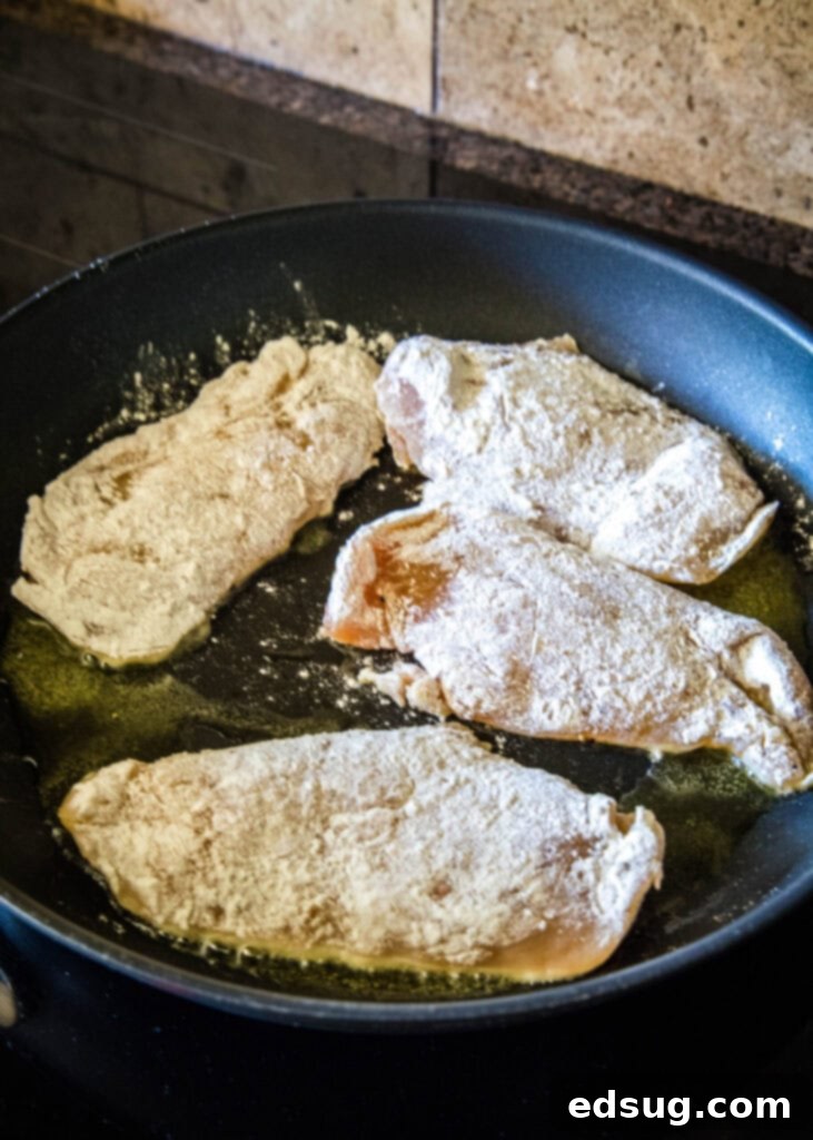 Easy and comforting chicken with mushroom sauce has juicy and tender meat smothered in a rich, herbaceous, and garlicky mushroom cream sauce. Four chicken breasts coated in seasonings and flour cooking in a skillet