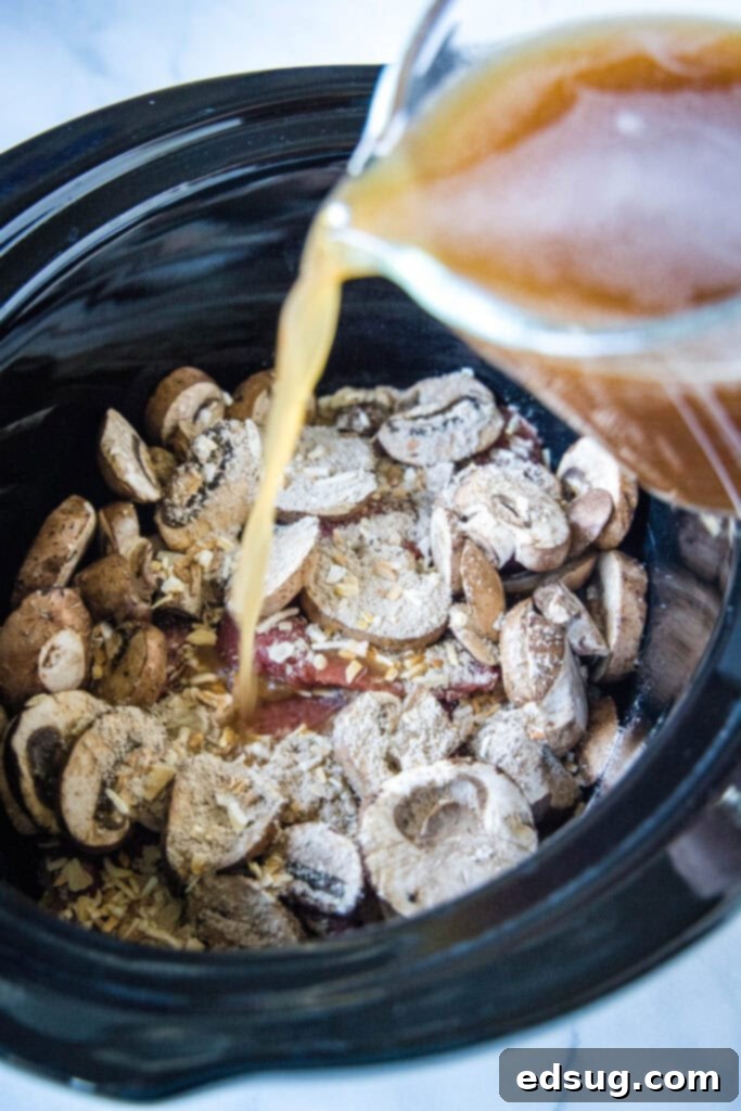 Tender Slow Cooker Cube Steak 4 pouring broth into crockpot with mushrooms and cube steak