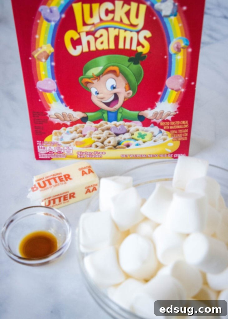 Lucky Charms Rainbow Krispie Delights 3 Ingredients laid out for Lucky Charms Rice Krispie Treats: cereal, marshmallows, butter, vanilla extract