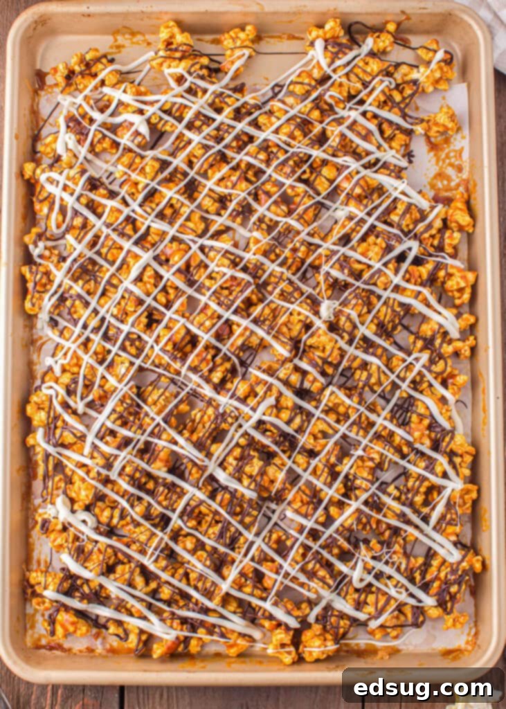white chocolate and chocolate drizzled over caramel popcorn on a baking tray